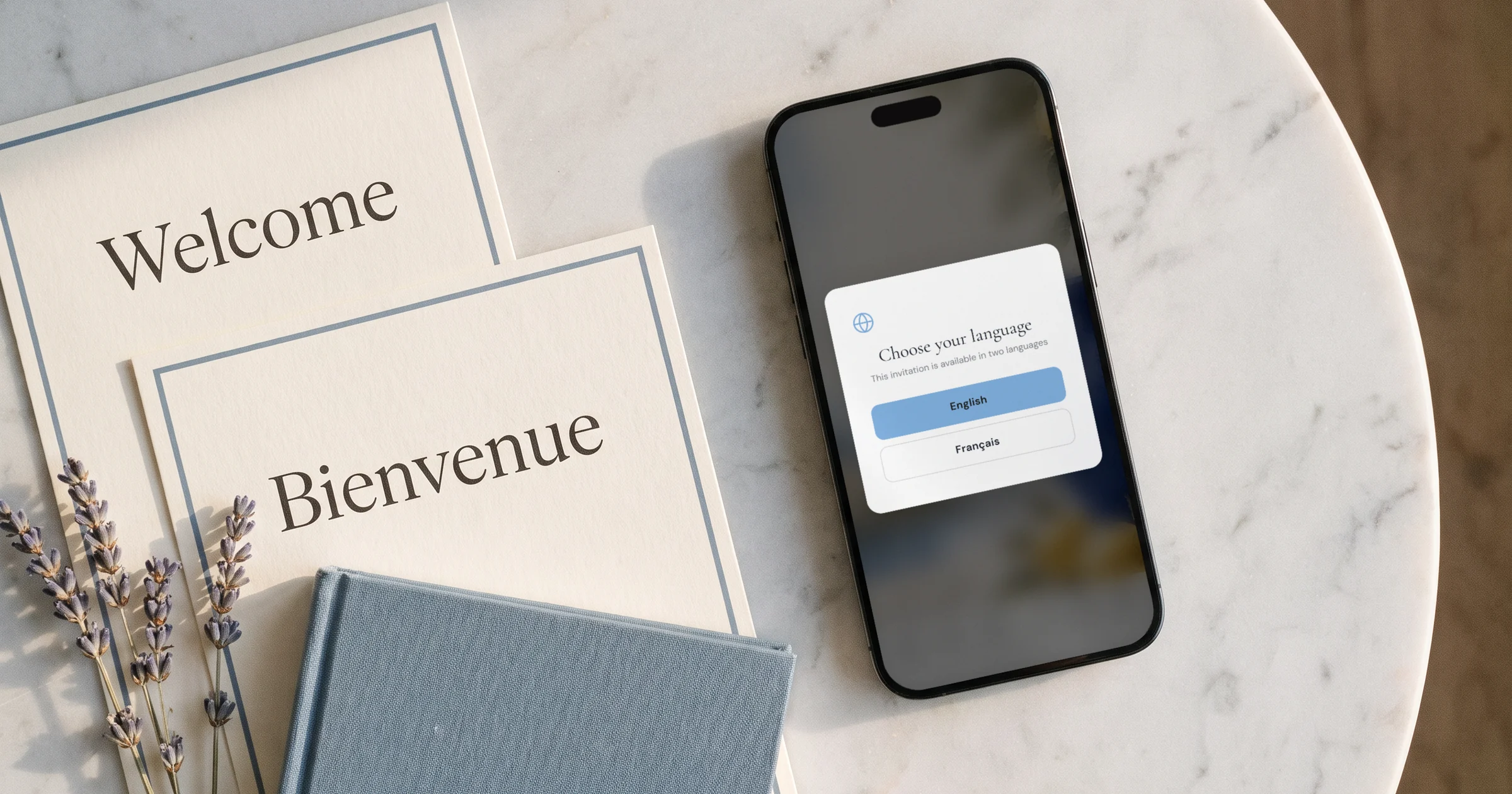 Best bilingual wedding websites 2026: a phone shows a wedding website language switcher next to two printed invitations in English and French