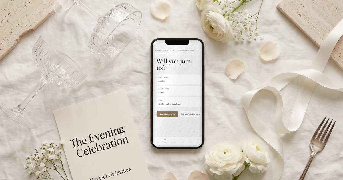 Evening wedding invitation RSVP on a phone - The Private Wedding App's guest reply form with Joyfully accepts button, lying flat on ivory linen beside a printed The Evening Celebration card, champagne coupes, white ranunculus and silk ribbon